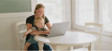 Mother and child smiling at computer screen.